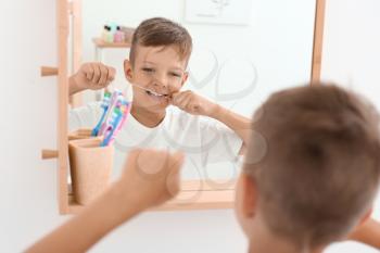 Little boy flossing teeth in bathroom�