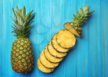 Slices of ripe pineapple and whole fruit on wooden background�