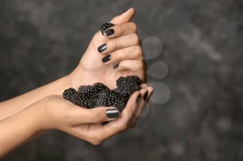Hands of beautiful young woman with professional manicure holding blackberry on dark grey background�