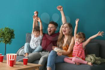 Happy family watching TV on sofa at home�