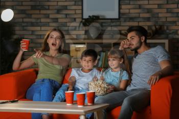 Family watching TV on sofa in evening�