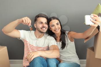 Young happy couple taking selfie with house key at new home�