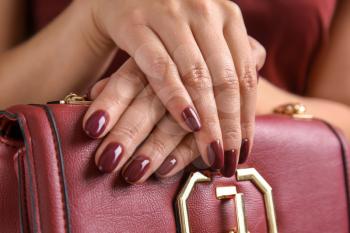 Hands of beautiful young woman with professional manicure holding purse, closeup�