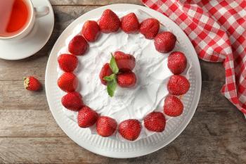 Delicious cake with strawberries on wooden table�