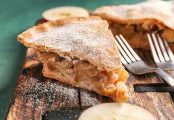 Pieces of tasty apple pie on wooden board, closeup�