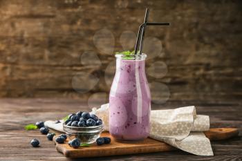 Glass bottle of tasty blueberry smoothie on wooden table�