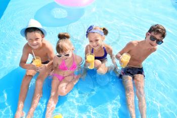 Cute children with glasses of juice in swimming pool on summer day�