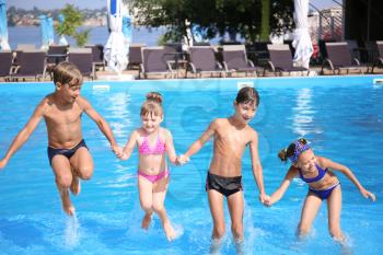 Cute children playing in swimming pool on summer day�