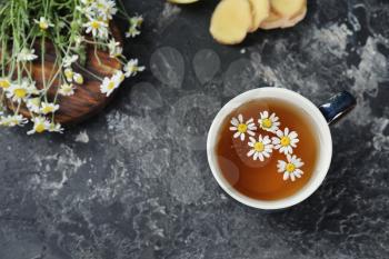 Cup of delicious camomile tea on grey table�