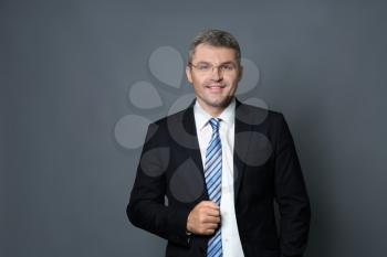 Handsome confident businessman on grey background�