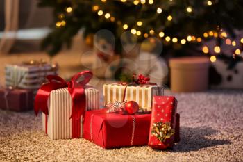 Beautiful Christmas gift boxes on floor near fir tree in room�