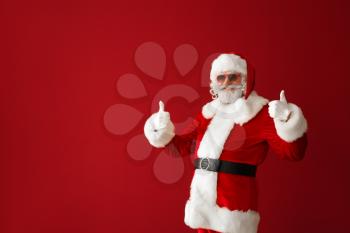 Portrait of cool Santa Claus showing thumb-up on color background�