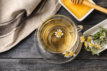 Cup of delicious camomile tea and honey on wooden table�
