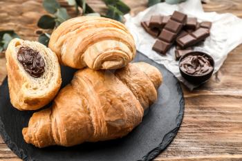 Tasty croissants with chocolate paste on slate plate�