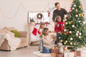 Happy family decorating Christmas tree in room�