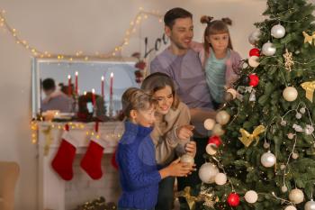 Happy family decorating Christmas tree in room�