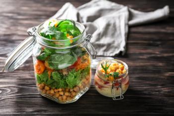Delicious vegetable salads in mason jars on wooden table�