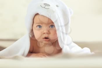 Cute baby with towel lying on bed at home�