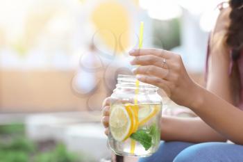 Young woman with mason jar of fresh lemonade outdoors, closeup�