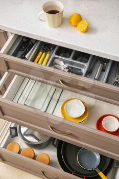Set of clean kitchenware and utensils in drawers�