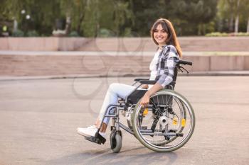 Happy young woman in wheelchair outdoors�