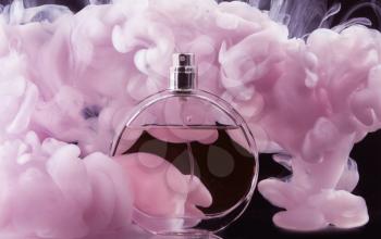 Bottle of perfume in color smoke on dark background�