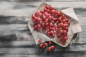 Tray with red grapes on wooden table�