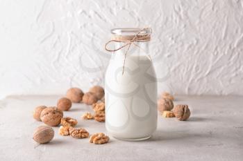 Bottle of tasty milk and walnuts on white table�