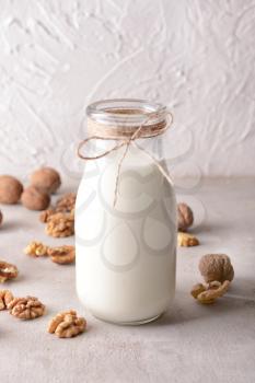 Bottle of tasty milk and walnuts on white table�