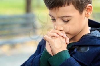 Little boy praying outdoors�