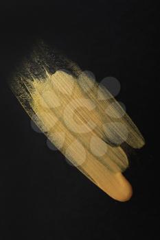 Strokes of gold paint on dark background�