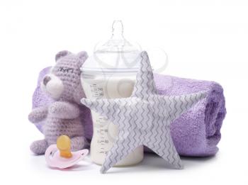 Feeding bottle of baby formula with toys and towel on white background�