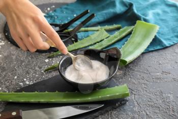 Woman preparing healing cream with aloe on grey table�