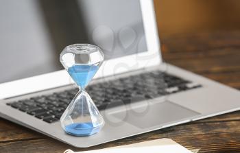 Hourglass on laptop keyboard. Time management concept�