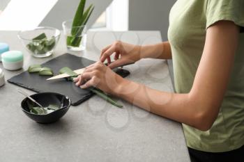 Woman cutting aloe leaf on slate plate�