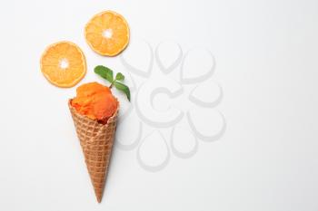 Waffle cone with delicious ice cream and orange slices on white background�