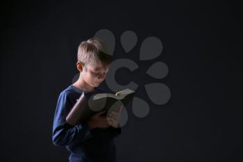 Little boy with Bible on dark background�