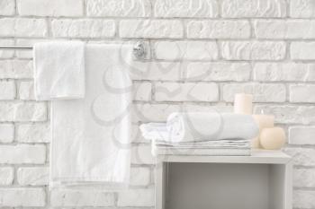 Towels with candles near white brick wall�