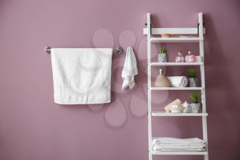 White clean towels and shelves with cosmetics on color background�