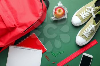 Cute rucksack with school stationery on color background�