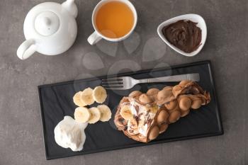 Plate with delicious sweet bubble waffle on grey table�