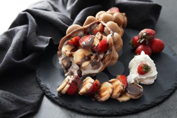 Delicious bubble waffle with ice cream and fruits on slate plate�