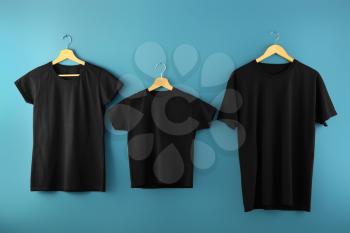 Hangers with blank t-shirts on color background�