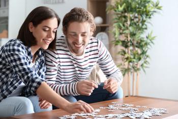 Young couple doing jigsaw puzzle at home�
