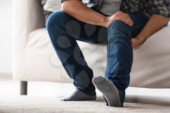 Man suffering from leg pain at home�