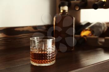 Glass of whiskey on wooden table�