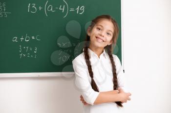 Cute girl standing near chalkboard in classroom�