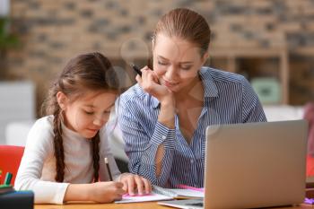 Cute girl with mother doing homework at home�
