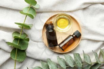 Bowl and bottles of eucalyptus essential oil on light cloth�