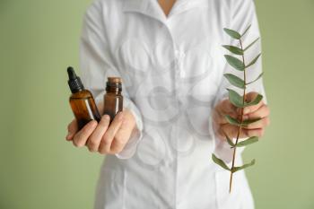 Pharmacologist with bottles of eucalyptus essential oil on color background�